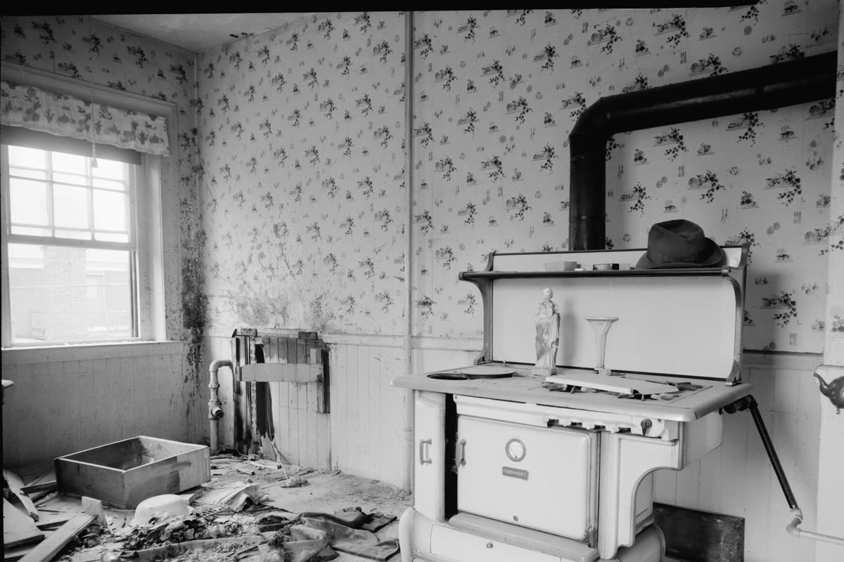 An old kitchen with a cast-iron range, a radiator under the window and papered walls, in Lowell, Massachusetts